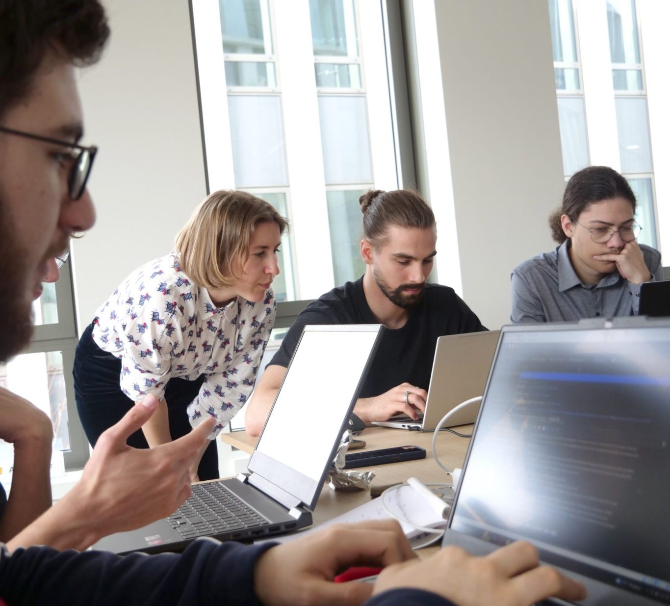 Groupe de personnes collaborant autour de plusieurs ordinateurs portables.